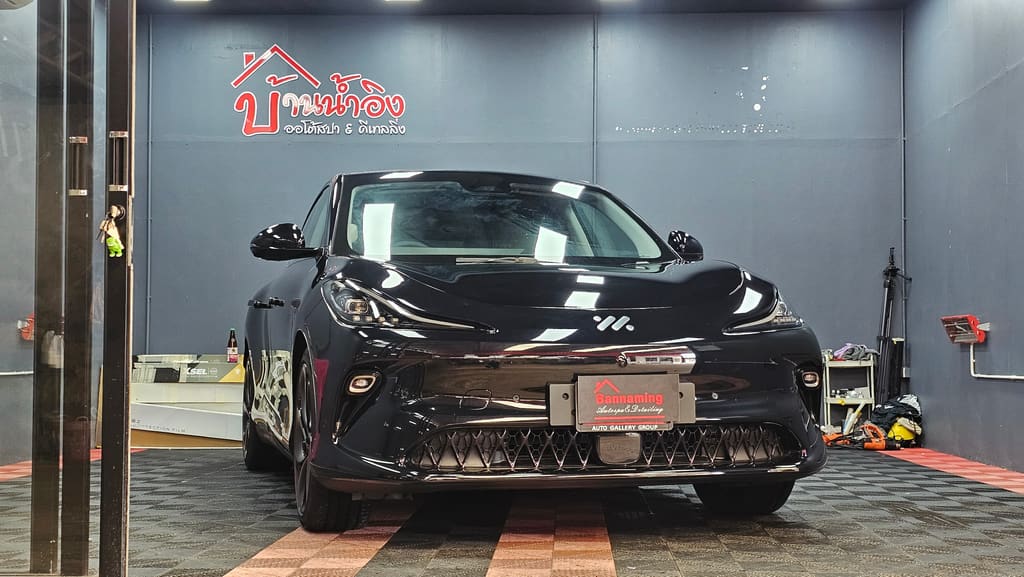 รถ MG IM6 สีดำเงา จอดในช่องทำงานของร้านบ้านน้ำอิง ออโต้สปา หลังติดฟิล์มกรองแสง